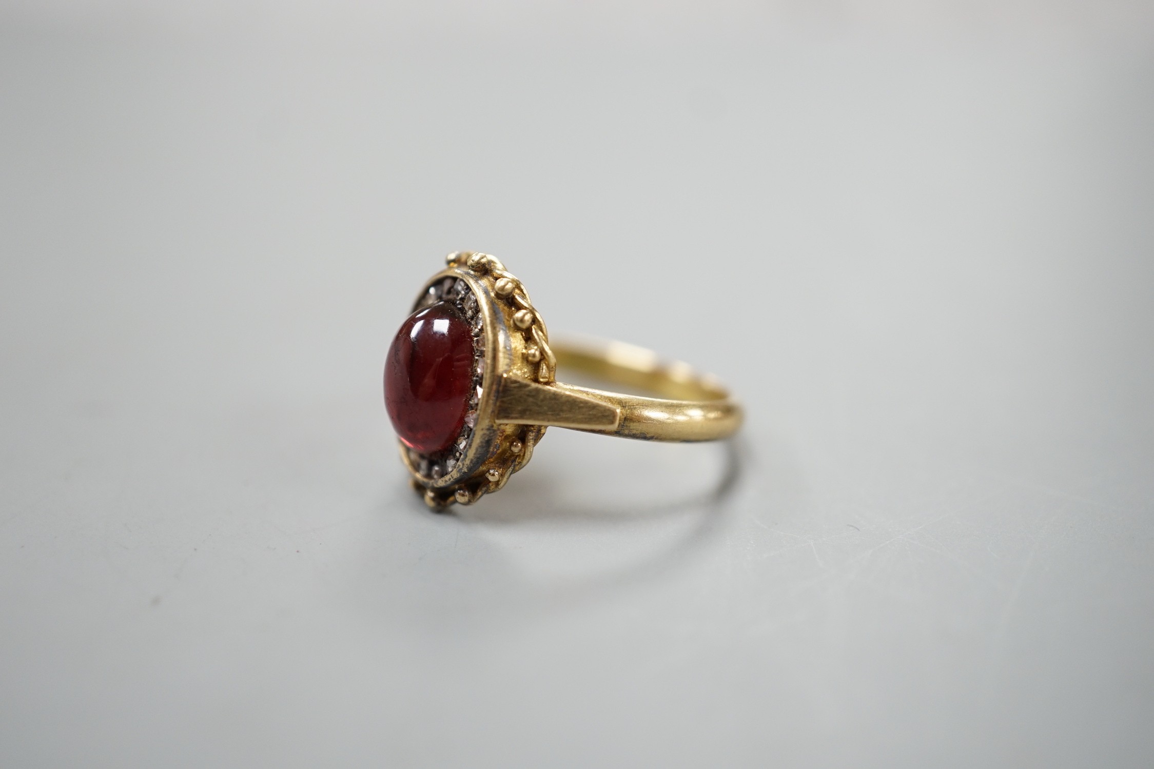 A Victorian style yellow metal cabochon garnet and rose cut diamond set oval cluster ring, size N/O, gross weight 5.2 grams.